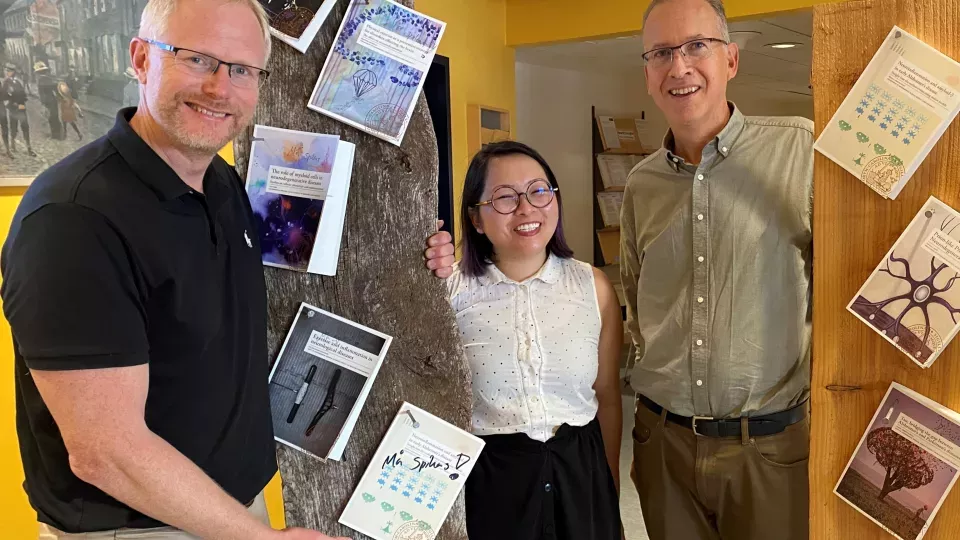 Megg Garcia Ryde's doctoral thesis is nailed to the boards of Neuroinflammation and Experimental Dementia Research. From left: supervisor Tomas Deierborg, PhD student Megg Garcia Ryde and supervisor Gunnar Gouras. Photo. 