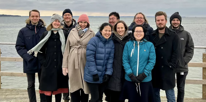 Group members together on a pier with the sea in the background